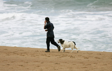 homme netrain de courir sur la plage avec son chien