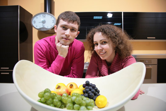 young couple on kitchen and vase with fruits