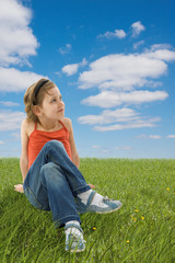 Fototapeta premium Cute girl sitting on the green grass