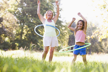 Fototapeta premium Grandmother and granddaughter at a park hula hooping and smiling