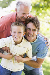 Grandfather with adult son and grandchild in park