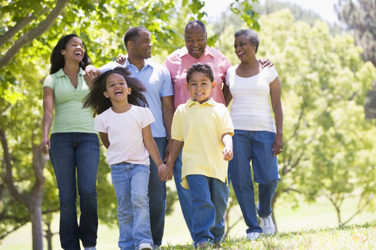 Extended Family Walking In Park Holding Hands And Smiling