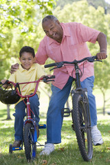 Grandfather and grandson on bikes outdoors smiling