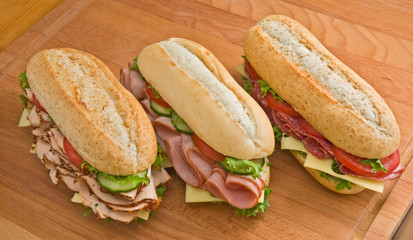 Turkey, ham and salami sandwiches on a wooden surface