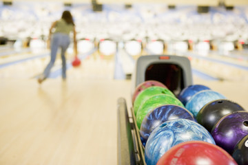 Bowling ball machine with woman bowling in the background