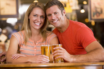 Happy young couple having beers at a bar