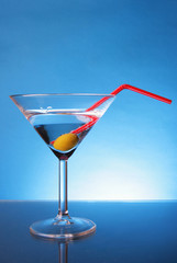 Cocktail glass with olive and red straw