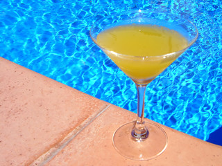 Glass of juice on pool edge