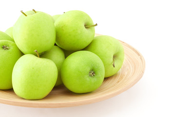 stack of green apples on wooden plate