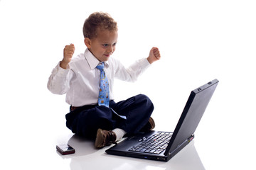 Young boy dressed as businessman works on his laptop computer -