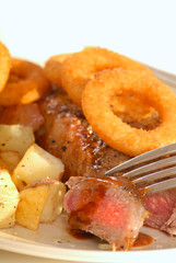 New York cut strip steak with potatoes and onion rings