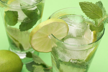 Two mojito cocktails on green background