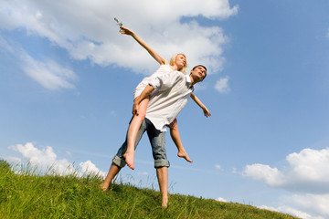 Fototapeta premium Happy Young Couple - jumping in the sky above a green meadow