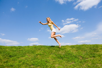 Happy young woman is running in a field