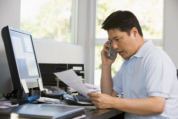 Fototapeta premium Man in home office with computer and paperwork on telephone