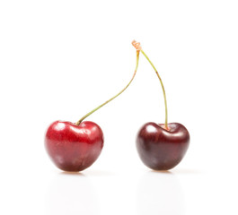 Two cherries against white background