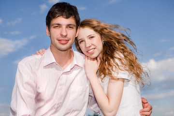 Portrait of a young happy couple against a backdrop of blue sky