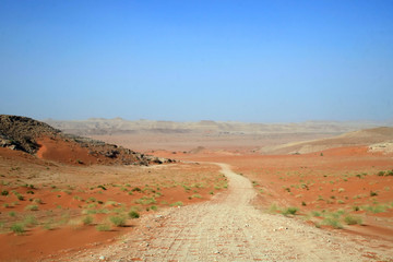Road through red sands desert in Saudi Arabia