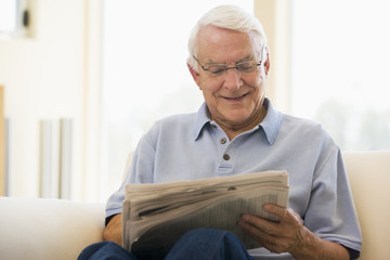 Man in living room reading newspaper