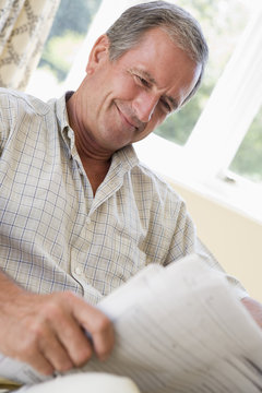 Man reading newspaper smiling