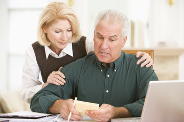 Couple with laptop and paperwork looking worried