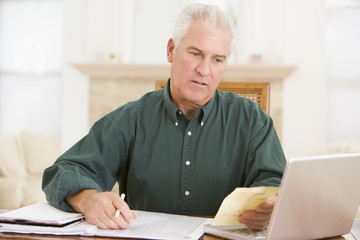 Man with laptop and paperwork looking unhappy
