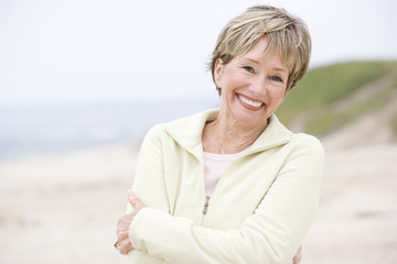 Fototapeta na wymiar Kobieta na plaży z rękami skrzyżowanymi uśmiecha