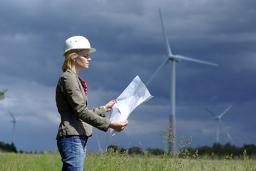 Woman engineer or architect with white safety hat and wind turbi