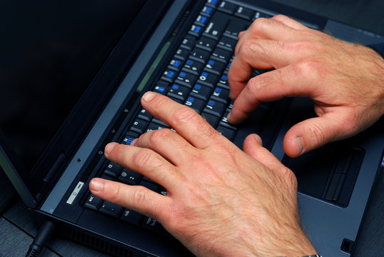 male hands typing on a black laptop