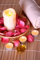 spa products with rose petals, oil container, towel and candles