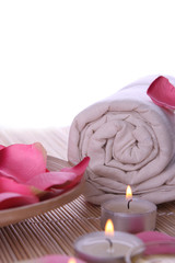 spa products with rose petals, oil container, towel and candles