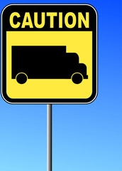 yellow caution sign with transport truck against blue sky 