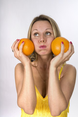 Blonde woman in yellow dress with two oranges in her hands