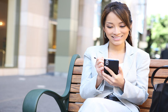 Asian Business Woman On Bench Outside Office