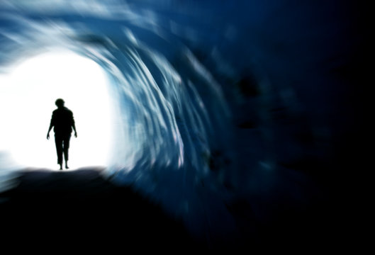 Silhouette d'une personne marchant vers une lumi&egrave;re &eacute;clatante au bout d'un tunnel sombre, concept de vie apr&egrave;s la mort, d'espoir, de spiritualit&eacute; et de renaissance.