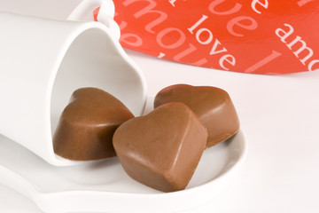 Three heart shaped chocolates on a heart shaped cup and saucer 