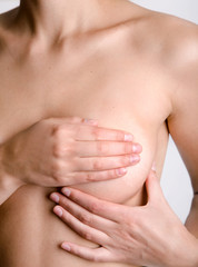 Young Caucasian adult woman examining her breast for lumps or si