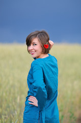 beauty young woman with poppy flower on storm sky background