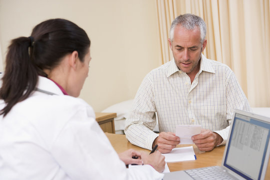 Doctor With Laptop And Man In Doctor's Office