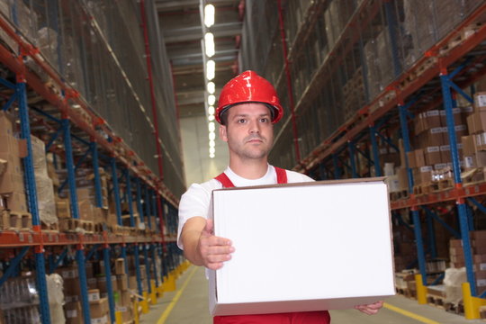 worker in uniform and hardhat carrying box in warehouse