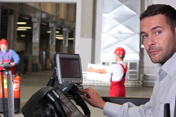 male operator pressing keys at control panel in warehouse