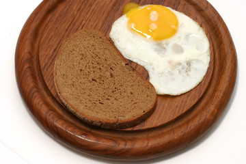 served fried egg on wooden plate with bread