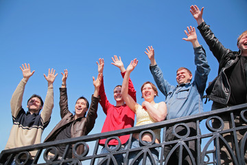 group of people stand with  hands lifted in  greeting