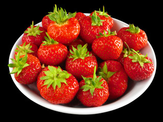 Strawberries in a white bowl isolated over black.
