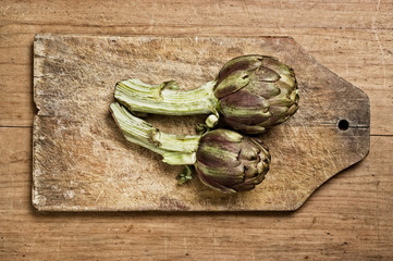 artichokes on a wooden cutting table, studio shot.
