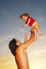 papa qui fait sauter son fils à la plage