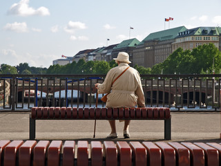 alte frau, die allein entlang des alsters sitzt