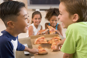 Four young children eating pizza smiling