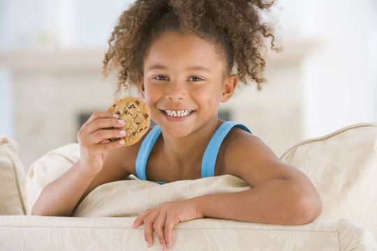 Young girl eating cookie in living room smiling