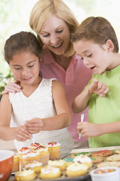 Woman with two children decorating cookies smiling